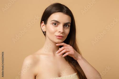 Close up brunette half naked woman 20s with perfect skin, nude make up isolated on beige pastel wall background, studio portrait. Skin care healthcare cosmetic procedures concept. Mock up copy space.