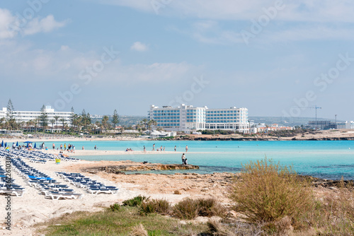 Fototapeta Naklejka Na Ścianę i Meble -  Umbrellas and chaise lounges on the beach. Plastic sunbeds near the sea. Tropical vacation, summer background.