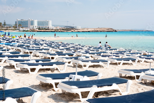 Umbrellas and chaise lounges on the beach. Plastic sunbeds near the sea. Tropical vacation, summer background.