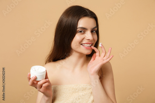 Close up half naked woman 20s with perfect skin nude make up applying facial cream isolated on beige pastel wall background  studio portrait. Healthcare cosmetic procedures concept. Mock up copy space