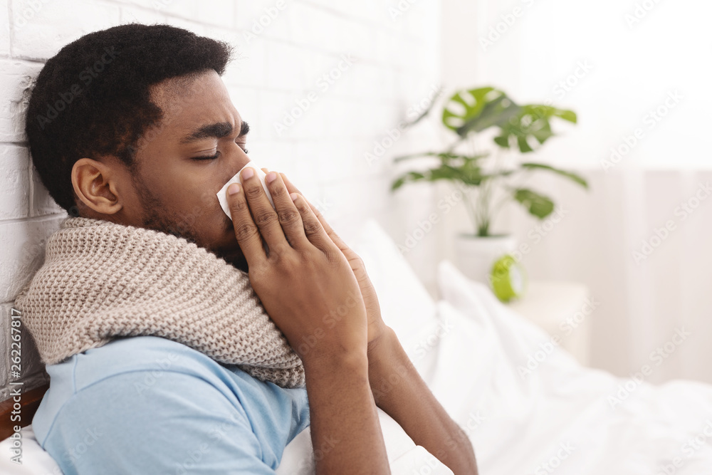 Young sick man in bed cleaning snotty nose Young sick man in bed cleaning snotty nose