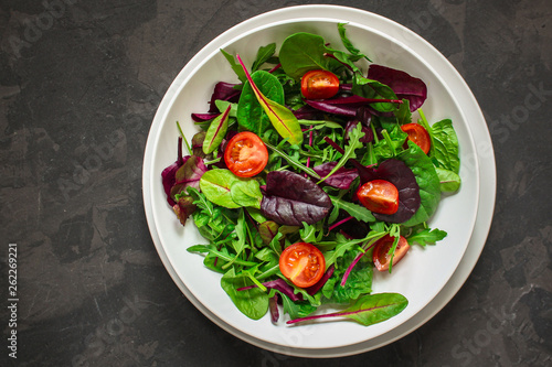 salad with tomato  lettuce  arugula  spinach and other leaves. food background. top