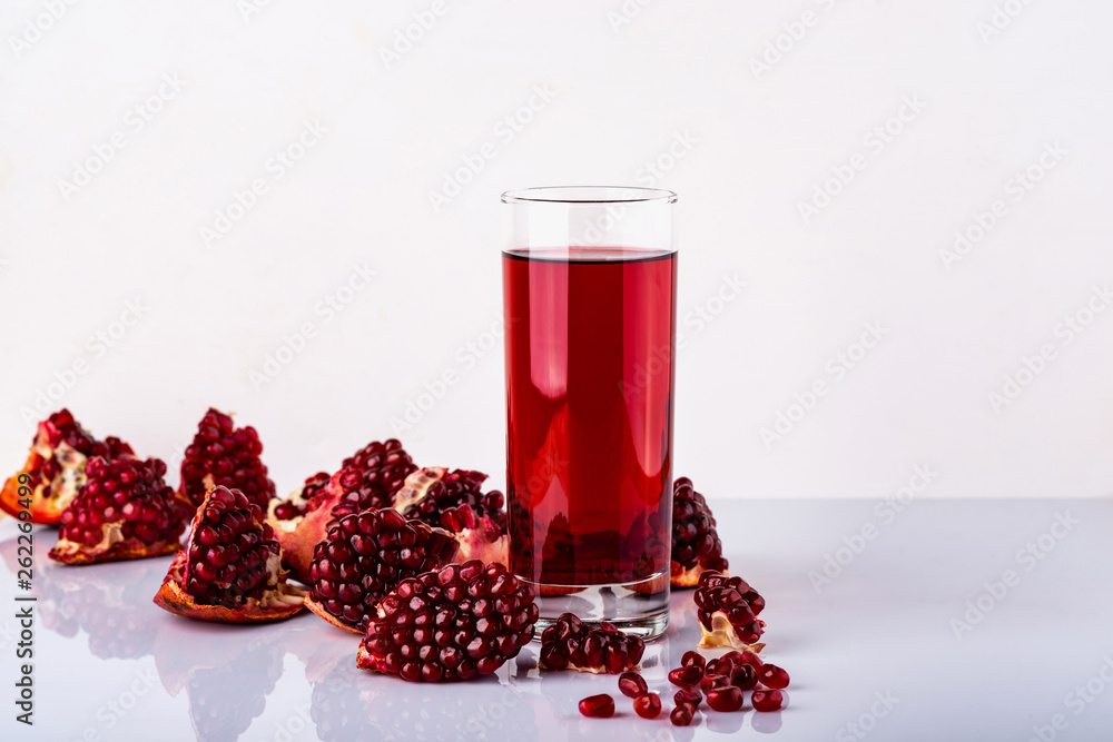 Glass of juice with a some pieces of pomegranate on a white background. Glass of juice with a some pieces of pomegranate on a white background.