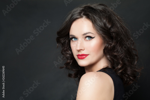 Happy woman model with makeup and brown curly hair on blackboard background