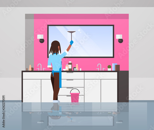 housewife in gloves and apron cleaning mirror with squeegee african american woman doing housework concept modern bathroom interior rear view female character full length