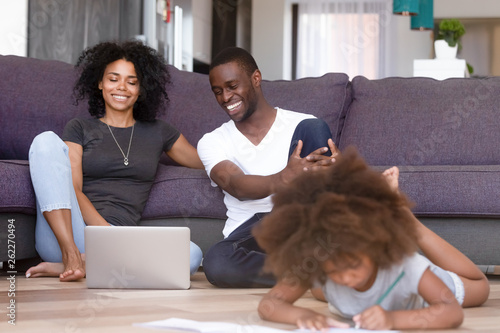 African American married couple using laptop while daughter playing