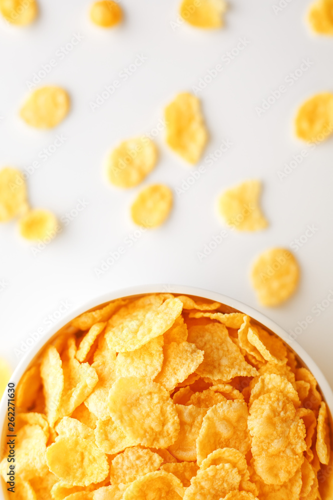 White cup with golden corn flakes, isolated on white background. Hopya crumbled around the cup. View from above. Delicious and healthy breakfast White cup with golden corn flakes, isolated on white background. Hopya crumbled around the cup. View from above. Delicious and healthy breakfast