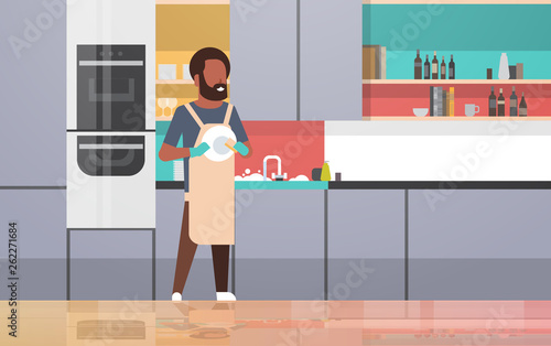 young man washing dishes african american guy wiping plates doing housework dishwashing concept modern kitchen interior flat horizontal full length