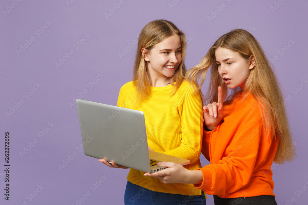 Two cheerful young blonde twins sisters girls in vivid colorful Two cheerful young blonde twins sisters girls in vivid colorful