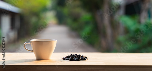 White coffee cup on a wooden table and coffee beans
