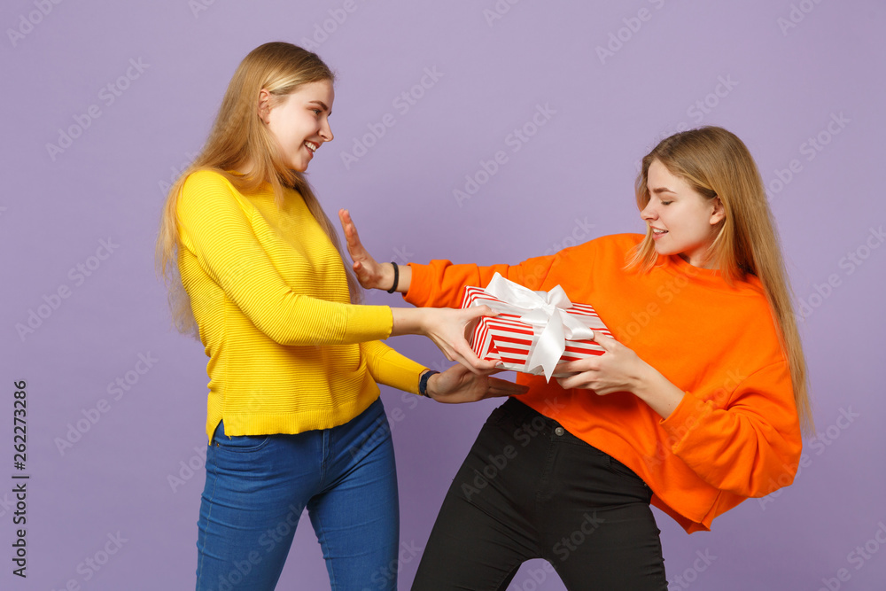 Two funny blonde twins sisters girls in vivid clothes holding re Two funny blonde twins sisters girls in vivid clothes holding re