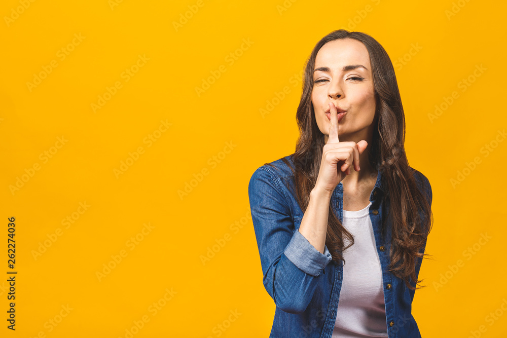 It's a secret! Shut your mouth. Finger on lips. Portrait of pretty cheerful female making shush or shh gesture with index finger over mouth, looking confident at camera over yellow background. It's a secret! Shut your mouth. Finger on lips. Portrait of pretty cheerful female making shush or shh gesture with index finger over mouth, looking confident at camera over yellow background.
