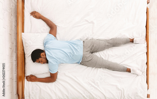 Young african-american man sleeping in bed top view photo