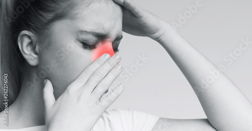 Unhealthy woman in pain touching her head and nose photo