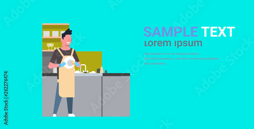 young man washing dishes guy wiping plates on kitchen doing housework dishwashing concept flat horizontal copy space full length