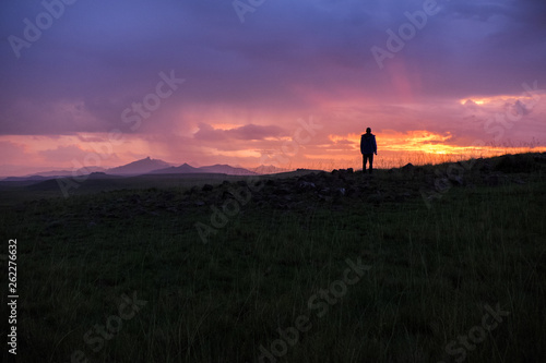 Sunrise landscape with the silhouette of a person, mountains and orange and pink sky, Lesotho, Africa