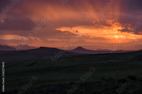 Sunrise landscape with mountains, clouds and orange sky, Lesotho, Africa
