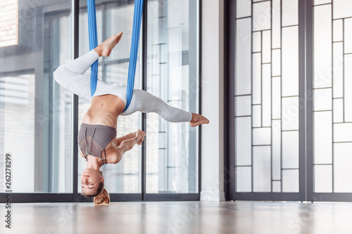 Beautiful female gymnast doing stretching on fabric hangers in a spacious hall during training. The concept of a flexible body and healthy joints photo