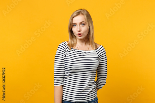 Beautiful confused young blonde woman in striped clothes looking camera isolated on bright yellow orange wall background, studio portrait. People sincere emotions lifestyle concept. Mock up copy space