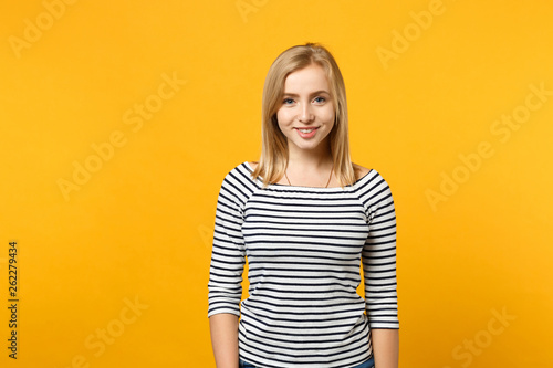 Beautiful smiling young blonde woman in striped clothes looking camera isolated on bright yellow orange wall background, studio portrait. People sincere emotions lifestyle concept. Mock up copy space.