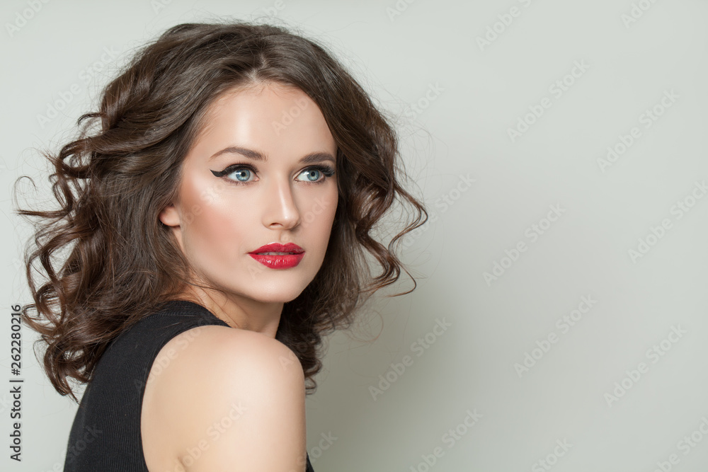 Fototapeta premium Cute model woman with makeup and perfect curly hair on white, portrait