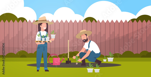 couple farmers planting young seedlings plants flowers and vegetables man woman working in garden eco farming concept backyard background flat full length horizontal