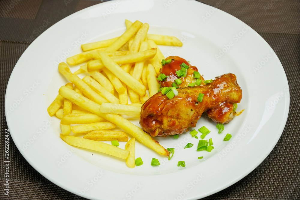Fried potatoes with chicken legs and chopped green onions on a plate Fried potatoes with chicken legs and chopped green onions on a plate