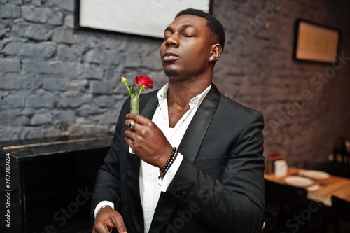 Quadro em tela Strong powerful african american man in black suit sniff flower in test tube against piano