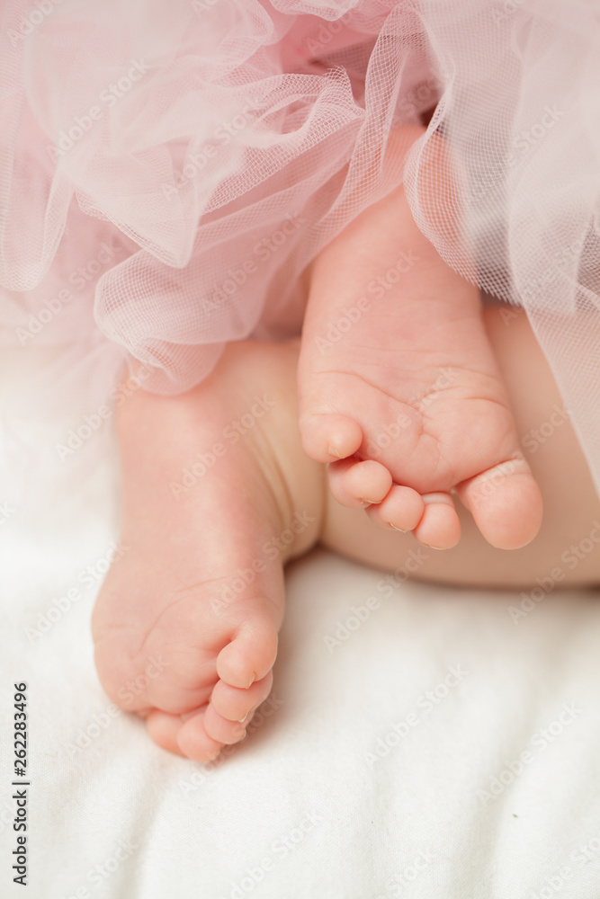Baby girls feet with tulle dress on white Baby girls feet with tulle dress on white