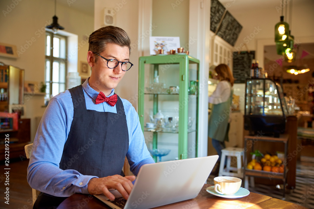 Small business owner sitting in cafe and working on his laptop Small business owner sitting in cafe and working on his laptop