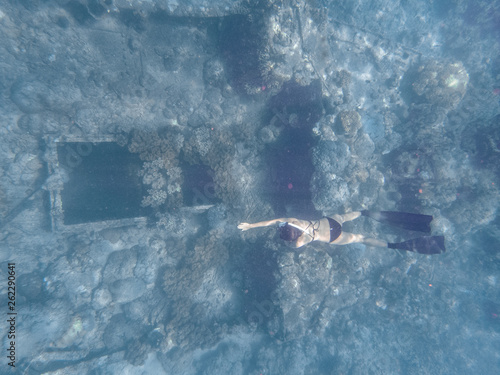 Young woman dives into a shipwreck in a sexy bikini swim wear.