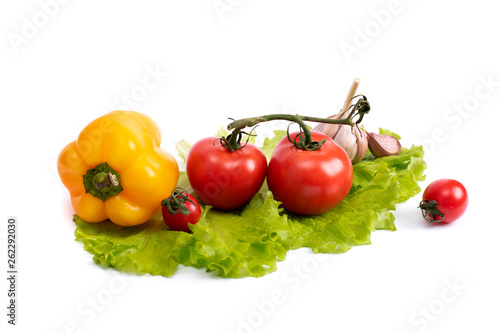 Yellow sweet pepper and red tomatoes on a leaf of green salad. Yellow pepper and tomatoes on a white isolated background. Tomatoes with yellow pepper on a white background.