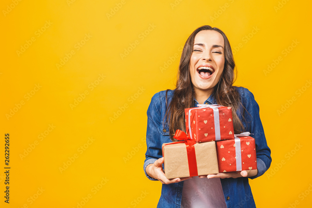 Young smiling model hold gift box. Woman isolated on yellow background. Young smiling model hold gift box. Woman isolated on yellow background.