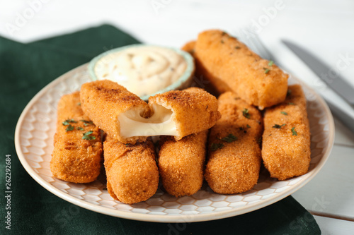 Plate of cheese sticks with sauce on table, closeup