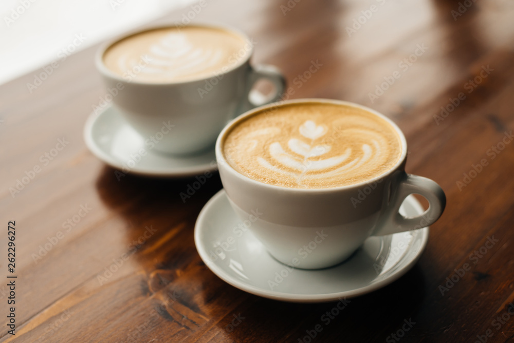 Two cups of fresh cappuccino on the wooden table. Two cups of fresh cappuccino on the wooden table.