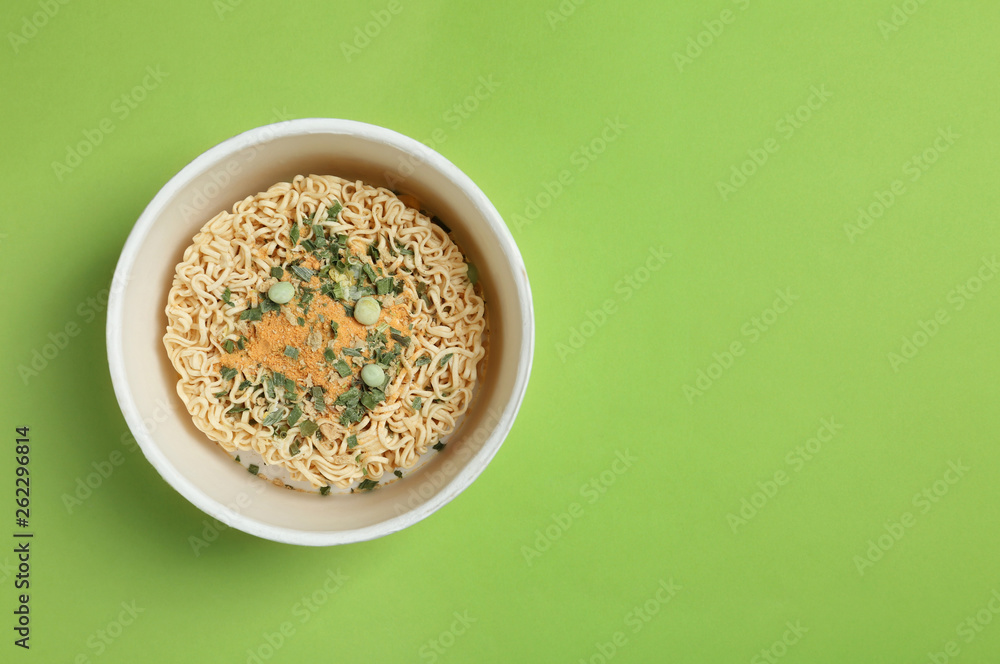 Cup of instant noodles on color background, top view. Space for text Cup of instant noodles on color background, top view. Space for text