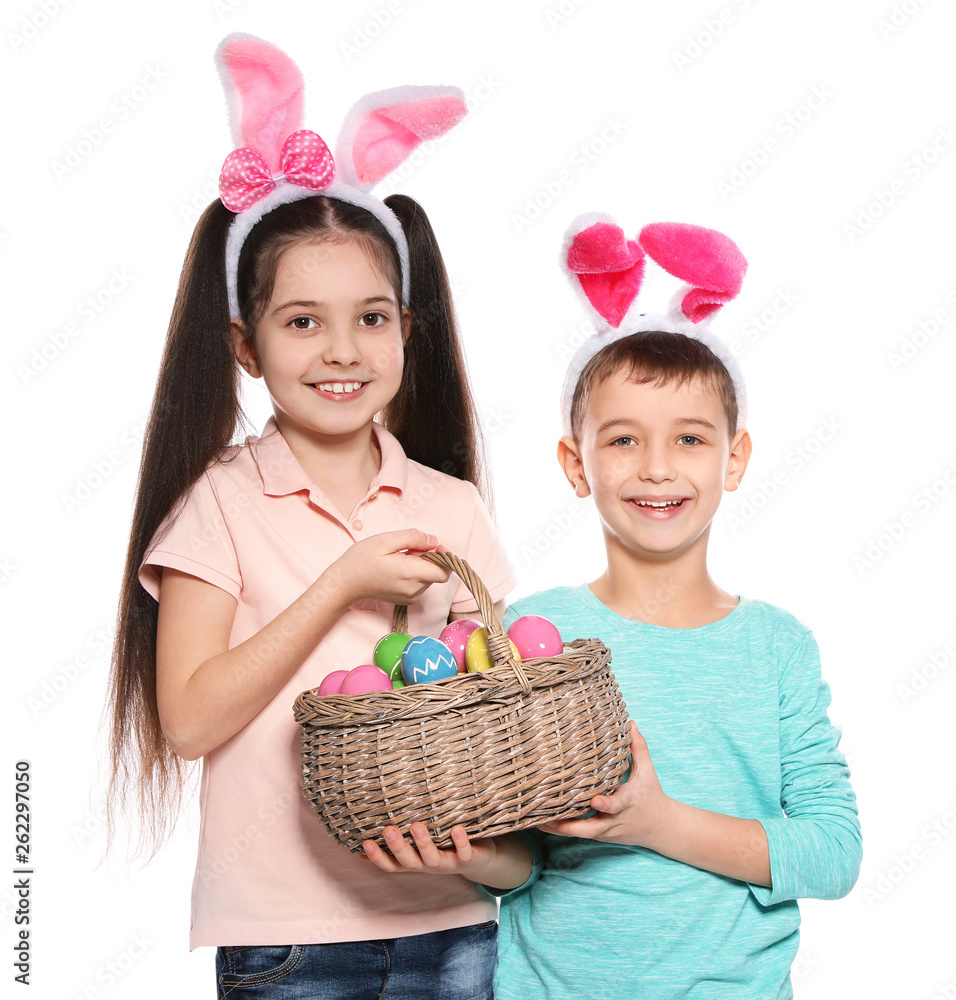 Cute children in bunny ears headbands holding basket with Easter eggs on white background