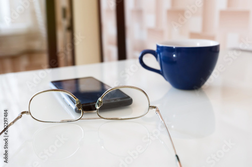Glasses for reading and a phone line on the table.