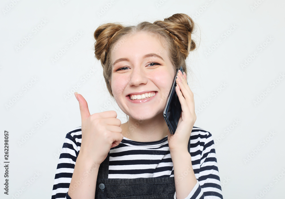 lifestyle and people concept: Portrait of a satisfied casual girl holding mobile phone and showing ok gesture isolated lifestyle and people concept: Portrait of a satisfied casual girl holding mobile phone and showing ok gesture isolated