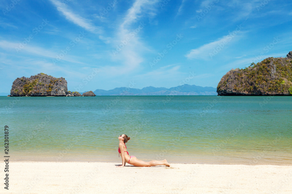 Young woman practice yoga on a beach