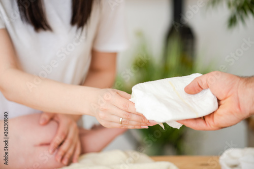 Male hand give diaper for female with baby