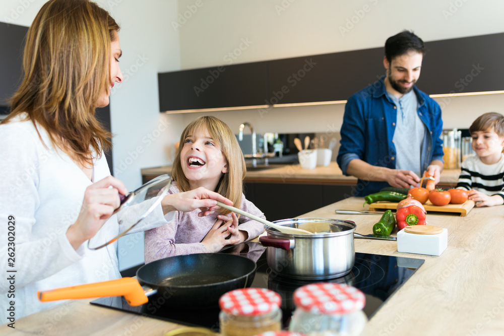 Beautiful cute family having fun while cooking together in the kitchen at home.