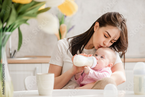Cuadro en lienzo Young woman kiss baby during drinking milk