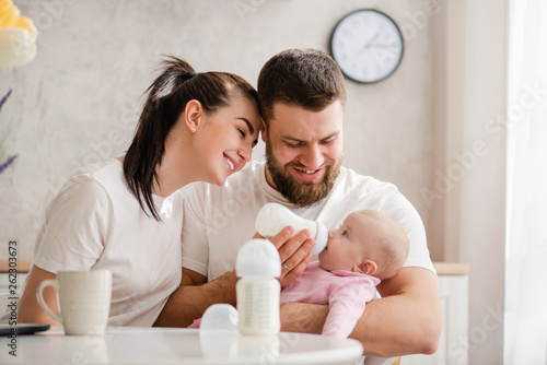 Schilderij op canvas Happy young couple feeding infant from bottle