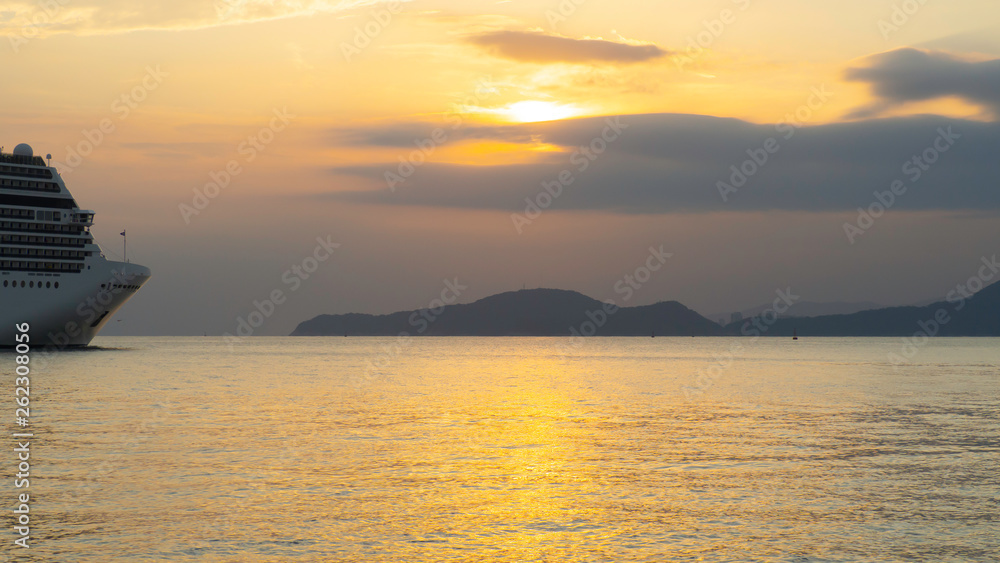 Cruise liner starting voyage surrounded by beautiful sunset light and hills in the background
