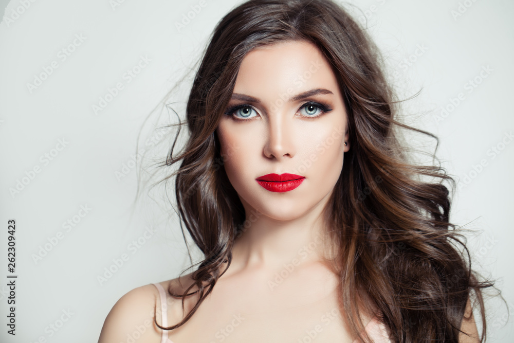 Stylish brunette model portrait. Beautiful woman with long curly hair and makeup on white background Stylish brunette model portrait. Beautiful woman with long curly hair and makeup on white background
