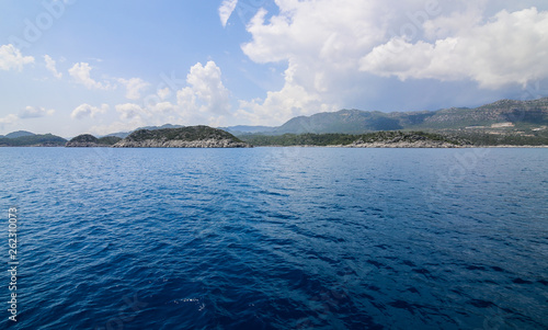 a view of the yacht on the blue waters and the various mountain scenery on the blue sky; travel pleasure in summer