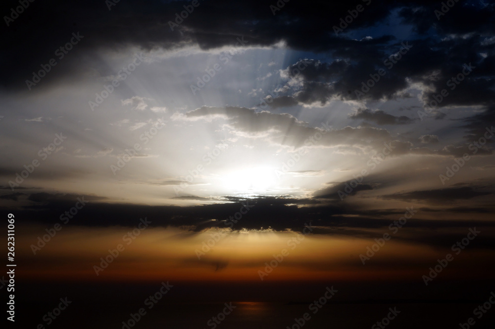 Strong sun light rays striking from behind clouds at sunrise Strong sun light rays striking from behind clouds at sunrise