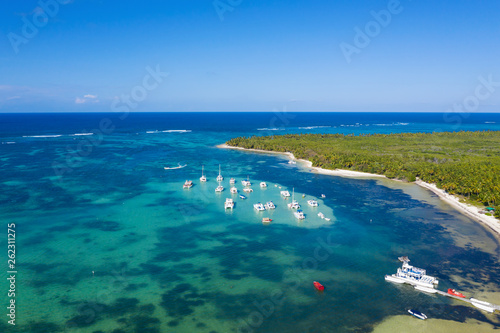 Aerial view on tropical beach with palm trees and speed boats shipping in caribbean sea