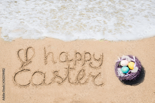Canvas Print Happy easter lettering background with eggs on the sandy beach